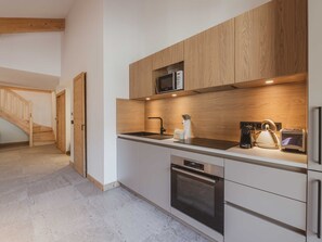 A modern kitchen with wooden cabinetry, a built-in microwave, a kettle, and a toaster. - Bright duplex, parking - 6 guests (Morzine)