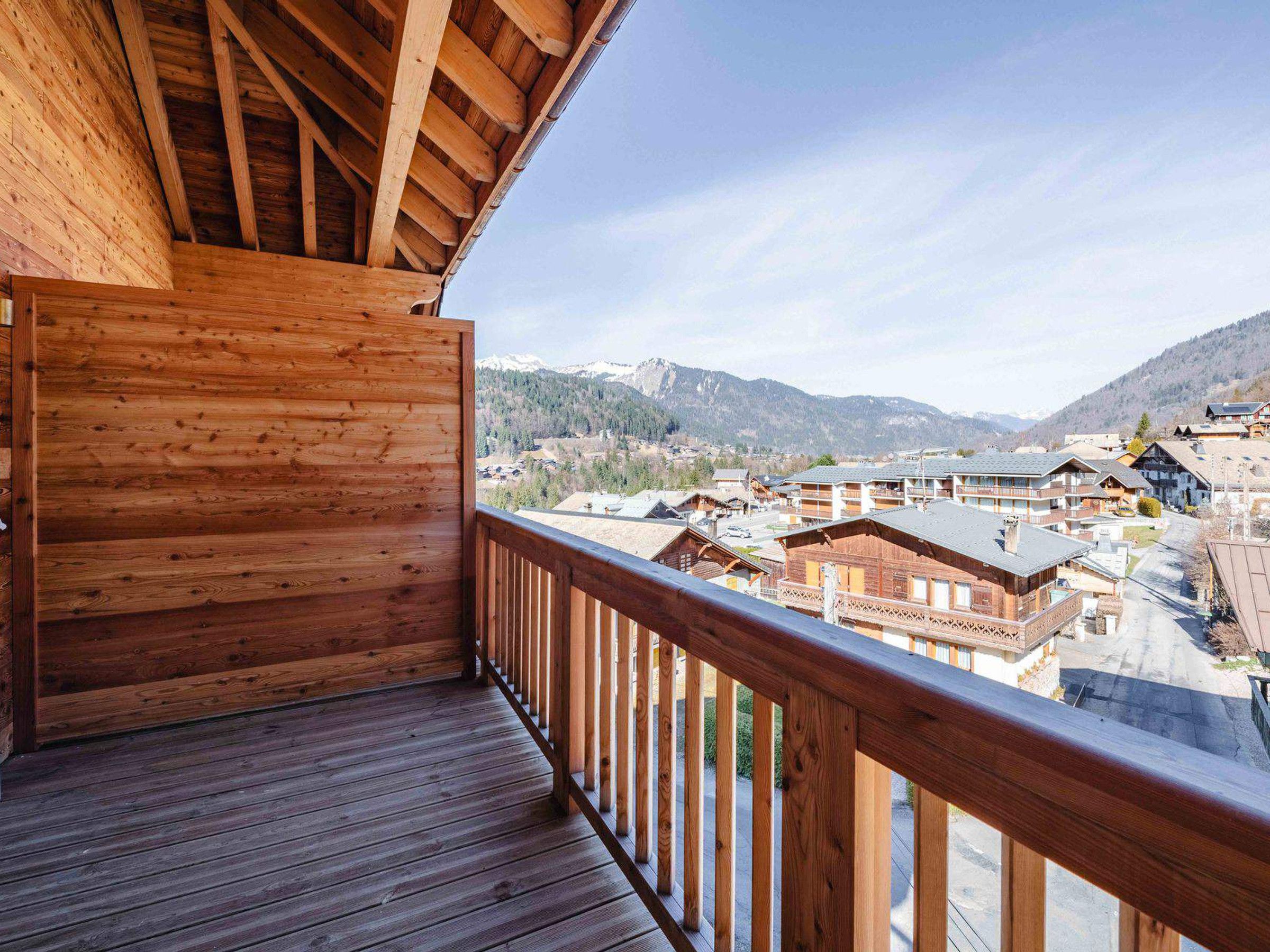 A wooden balcony with a view of a mountainous town.