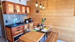 Una cocina con armarios de madera, una encimera, una mesa de comedor y lámparas colgantes.