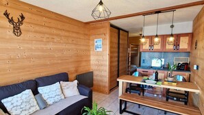 Una habitación acogedora con una pared de madera, un sofá, una mesa de comedor y una zona de cocina.