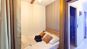 Una cama individual con cabecera de madera, una lámpara colgante y una puerta que da a otra habitación.