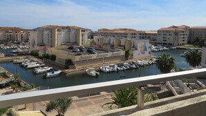 Un puerto deportivo con barcos amarrados, una zona de estacionamiento y edificios de estilo arquitectónico uniforme.
