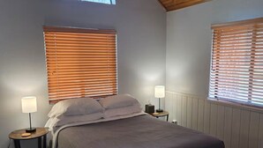 A bedroom with a bed, two bedside tables, a window with blinds, and a skylight. - Welcoming Suite in Idyllwild (Idyllwild-Pine Cove)