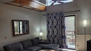 A modern living room with a sectional sofa, a round coffee table, a ceiling fan, and a skylight. - Welcoming Suite in Idyllwild (Idyllwild-Pine Cove)