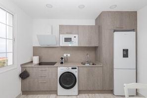 Una cocina moderna con lavadora, microondas y refrigerador.
