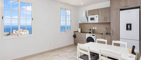 A modern kitchen with a washing machine, microwave, and refrigerator.
