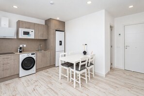 A modern kitchen with a washing machine, a microwave, and a refrigerator.