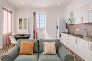 A compact living space with a sofa, dining table, and kitchenette. - GuestReady - El Refugio de Salomé Graja Real (Los Sauces)