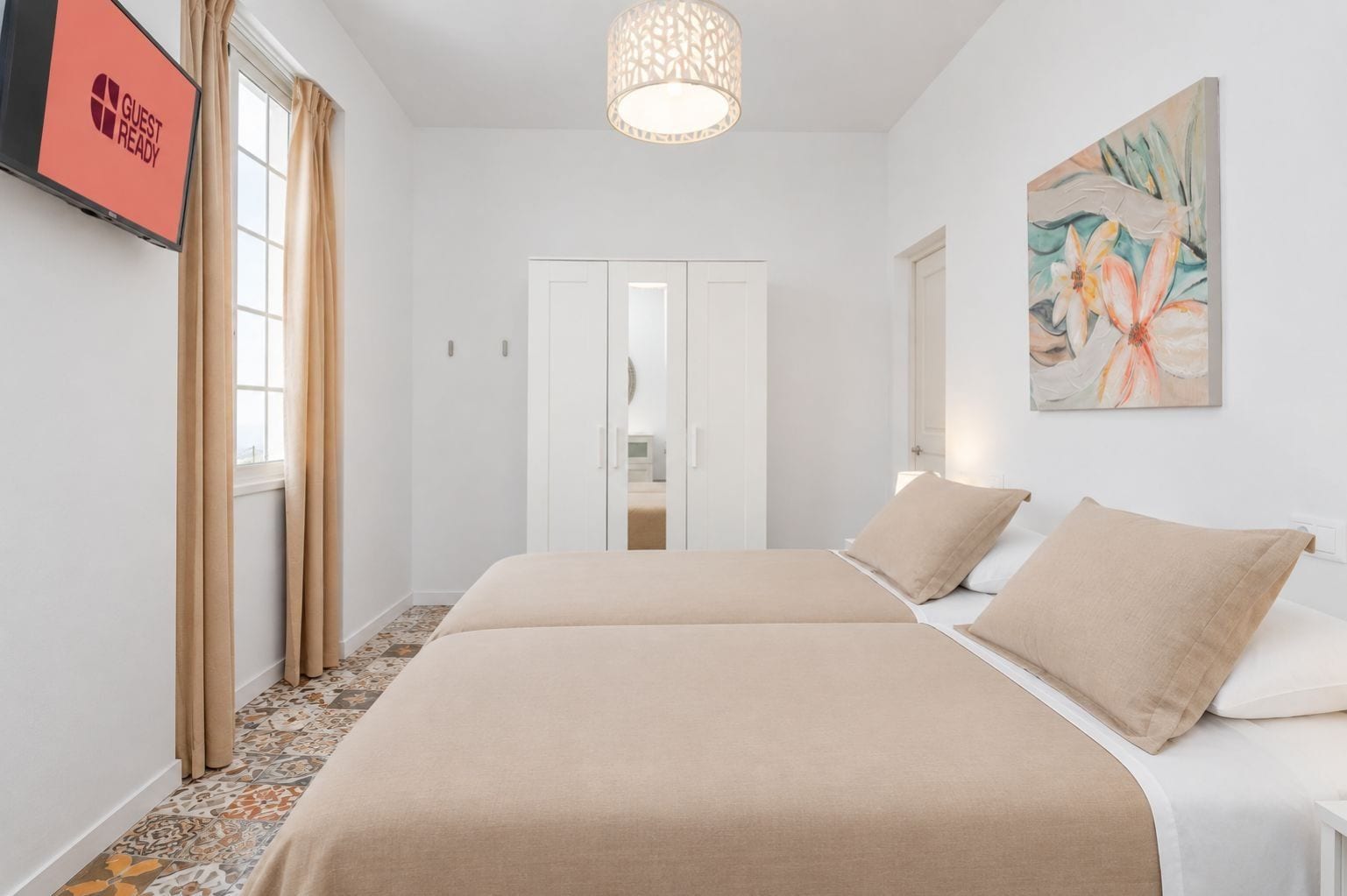 A hotel room with a bed, a television, a painting, and a wardrobe.