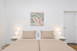 Una cama doble con dos almohadas, una mesita de noche con lámpara y un cuadro colgado en la pared.