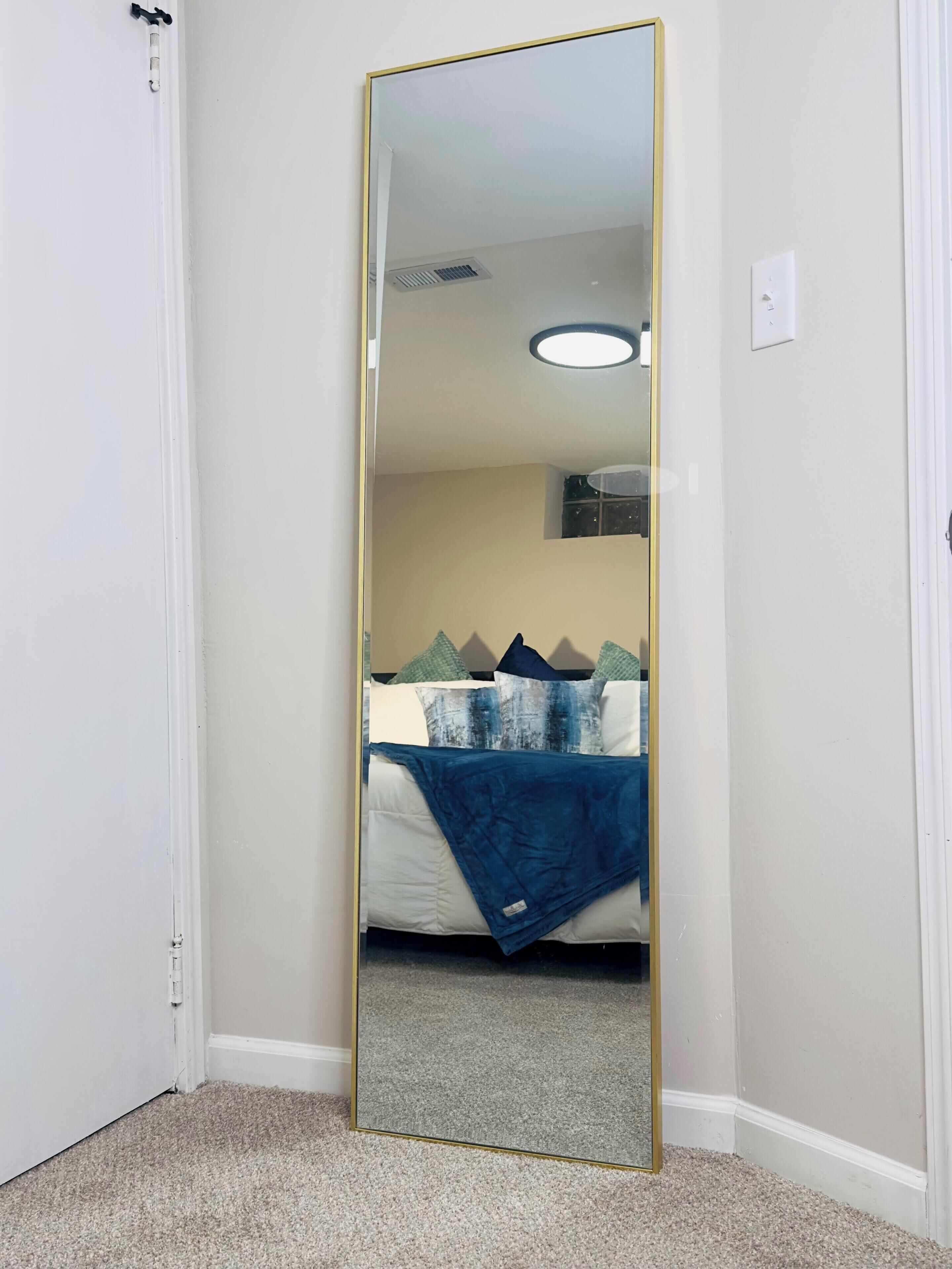 Un dormitorio con cama, espejo y piso alfombrado.