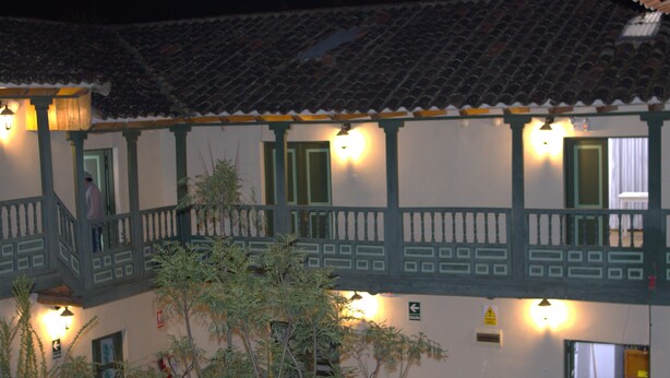 Un edificio con techo de tejas, balcones e iluminación exterior.