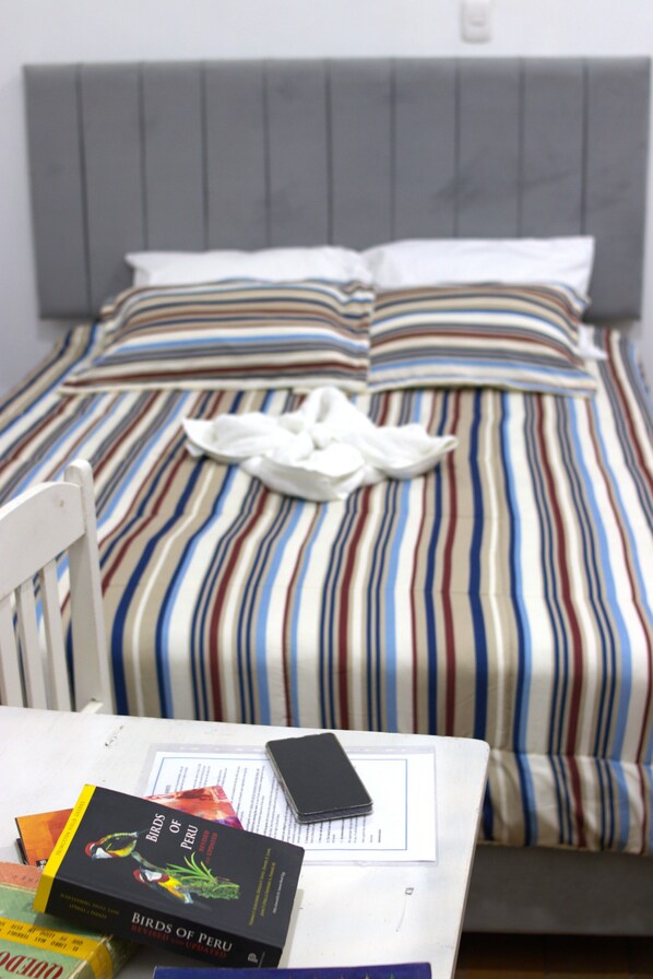 A bed with striped bedding, a white pillow, and a white blanket.
