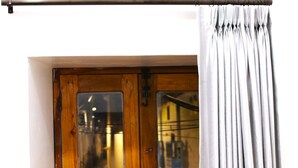 Una puerta de madera con ventanal, cortina y una barra de metal encima.