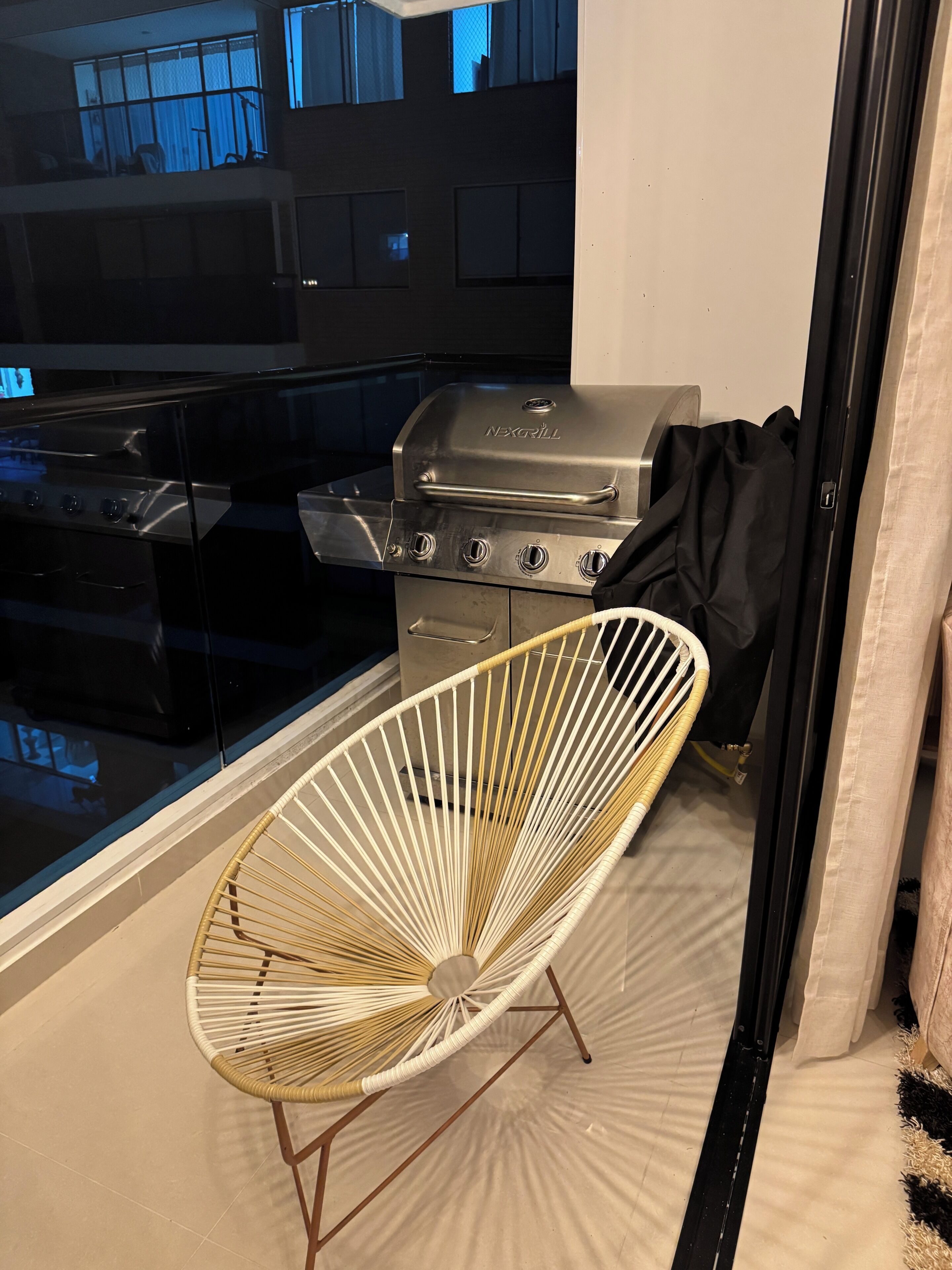Moderni keittiö, jossa on sisäänrakennettu liesi, grilli ja rottinkituoli.