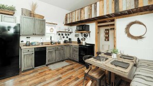 A kitchen with wooden cabinets, a dining table with placemats, and a microwave. - Lone Star Bungalow with Hiking & Lake access (Branson)