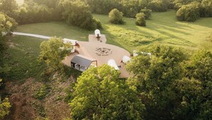 Vue aérienne d’une propriété dotée d’un espace circulaire central, entouré d’arbres et de champs ouverts.