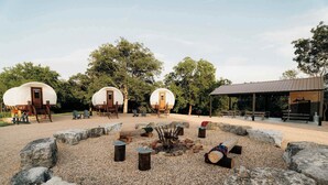 A campsite with three dome-shaped tents, a fire pit, and a covered seating area. - Cozy Couples Wagon | Lake Access + King bed (Branson)