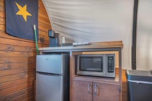 Eine kleine Küchenzeile mit Kühlschrank, Mikrowelle und Holzschränken.