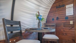 A wooden interior with a round table, two chairs, a vase with flowers, and a menu on the table. - Cozy Couples Wagon | Lake Access + King bed (Branson)