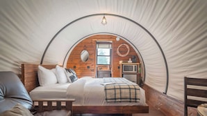 Una carpa con una cama, un banco de madera, una mesita y un tapiz de cuero de vaca.