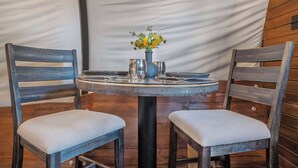 Una mesa redonda con un florero, dos sillas tapizadas y una pared de madera.
