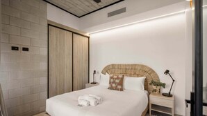 Ein modernes Schlafzimmer mit einem großen Bett, einem Holz-Kopfteil, Nachttischen und einem Kleiderschrank.