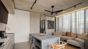 Eine moderne Küche mit einer zentralen Kochinsel, einem Essbereich mit einer Couch und einem Deckenventilator.