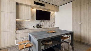 Eine moderne Küche mit Marmor-Spritzschutz, einem Flachbildfernseher, einem Holztisch und einem eingebauten Backofen.