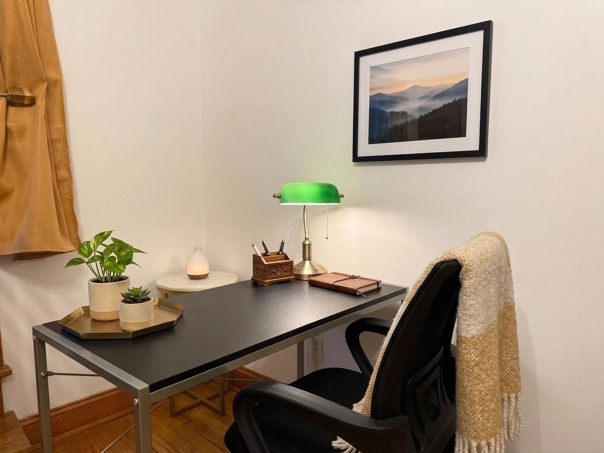 Un bureau avec une lampe, une plante, un carnet et un pot à crayons.