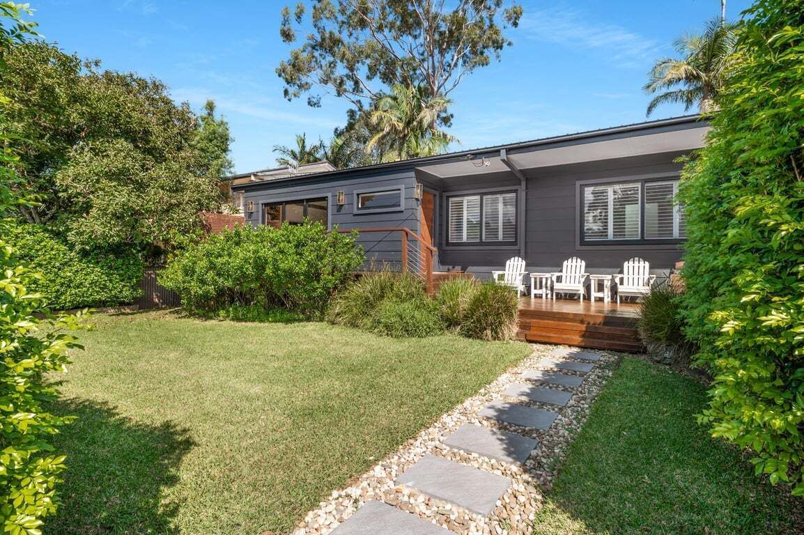 A modern house with a well-maintained lawn, a stone pathway, and outdoor furniture.