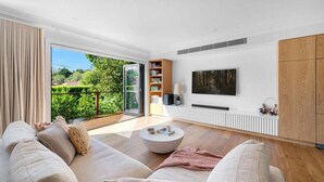 Ein modernes Wohnzimmer mit einer Couch, einem Couchtisch und einem an der Wand befestigten Fernseher.