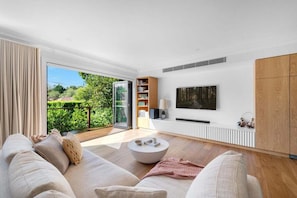 Ein modernes Wohnzimmer mit einer Couch, einem Couchtisch und einem an der Wand befestigten Fernseher.