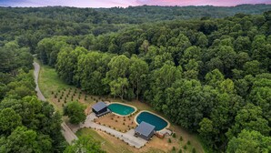 An aerial view of a property with two swimming pools, a guesthouse, and a forested landscape. - New Listing! Luxury Pondside Cabin | Hot Tub (McArthur)