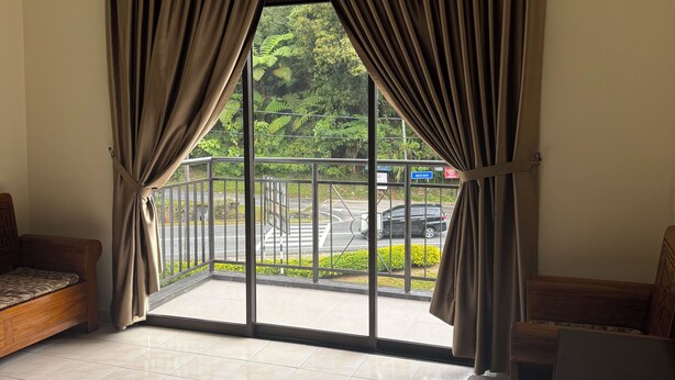 A room with a large sliding glass door, a sofa, a TV, and a tiled floor.