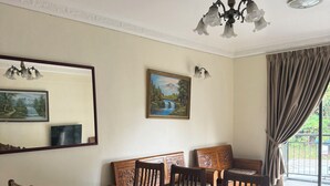 A dining area with a wooden table and chairs, a chandelier, and a painting on the wall.