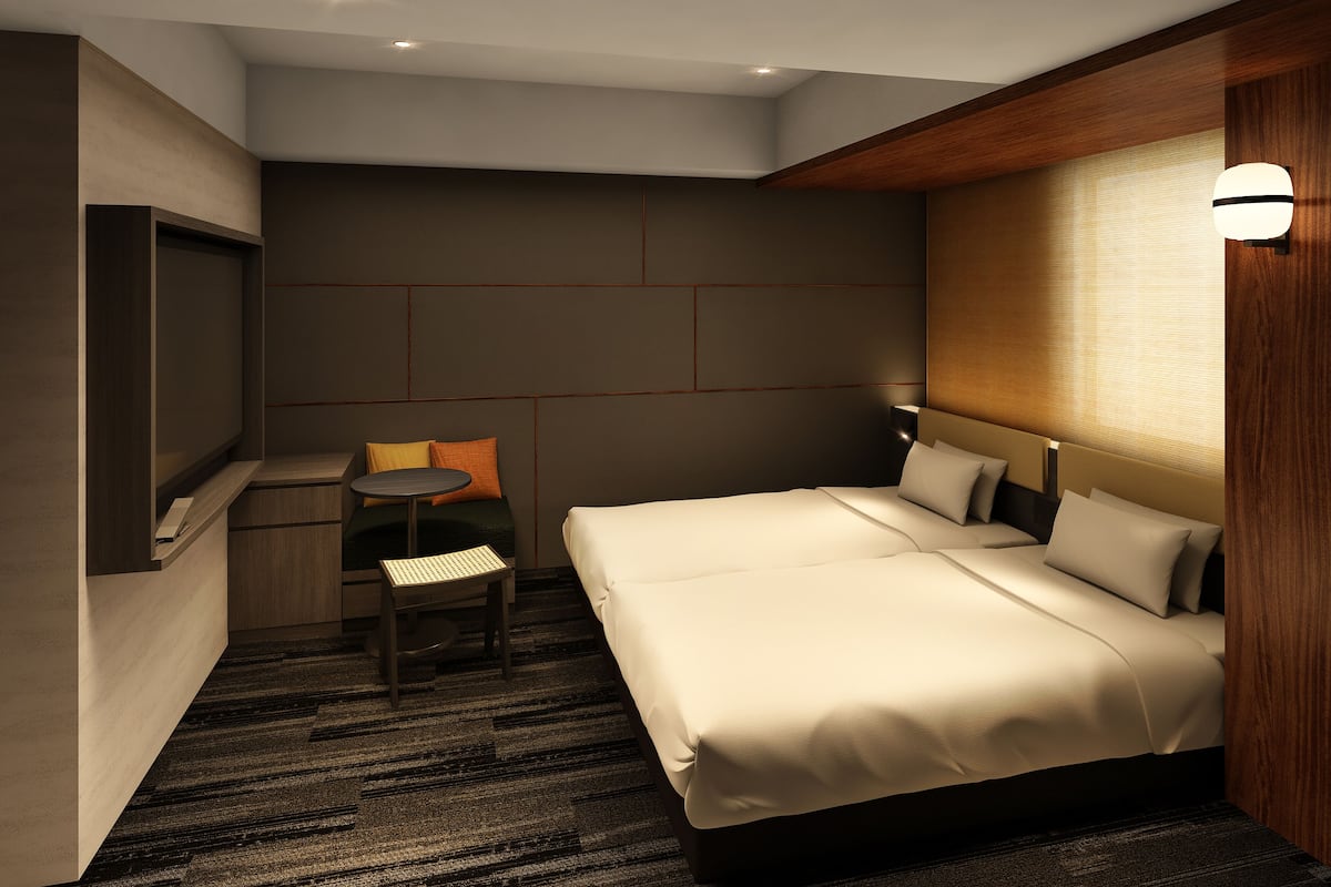 Ein modernes Hotelzimmer mit einem Bett, einem Schreibtisch, einem Sessel und einem Fernseher.