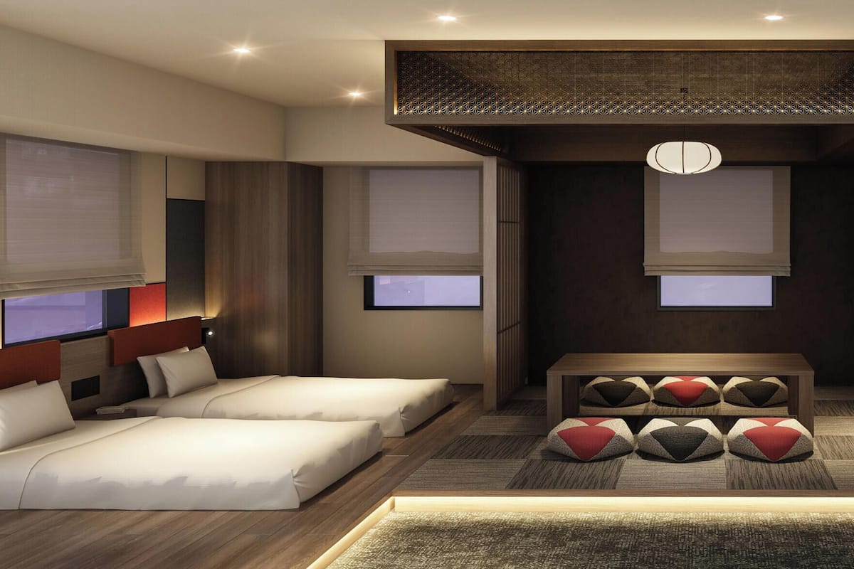Ein modernes Hotelzimmer mit zwei Betten, einer zentralen Sitzecke und einem großen Fenster.