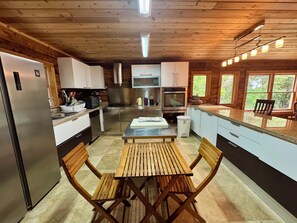 Een moderne keuken met houten kastjes, roestvrijstalen apparatuur en een eethoek met houten stoelen.