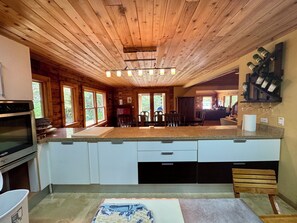 Une cuisine avec un plafond en bois, des plans de travail en granit et un four encastré.