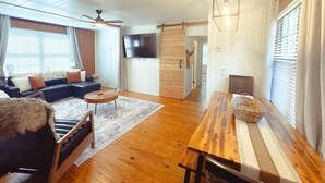 Een moderne woonkamer met een hoekbank, een houten eettafel en een televisie.
