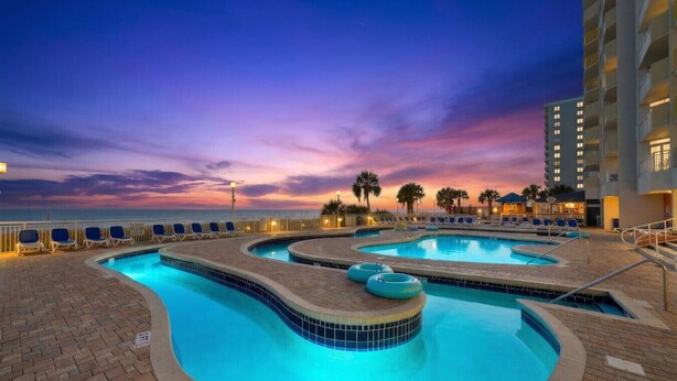 Un espace piscine avec des chaises longues et une vue sur le coucher de soleil.