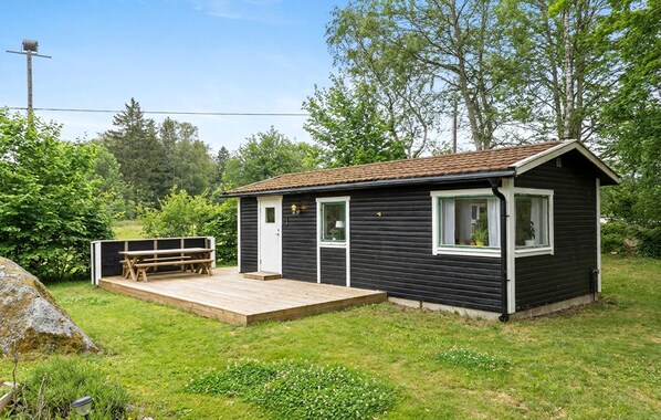 Een klein huisje met een terras, één deur en een raam.