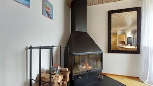 A room with a wood-burning stove, a mirror reflecting the room, and a painting on the wall. - Beautiful home in Tjörnarp with WiFi (Tjörnarp)