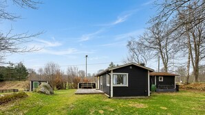 A small cabin with a deck, surrounded by a grassy yard and trees. - Beautiful home in Tjörnarp with WiFi (Tjörnarp)