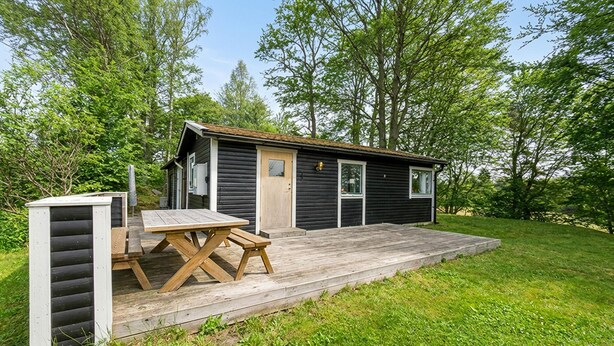 A small cabin with a wooden deck, a picnic table, and a covered outdoor seating area. - Beautiful home in Tjörnarp with WiFi (Tjörnarp)