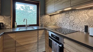 Eine moderne Küche mit eingebautem Geschirrspüler, einem Fenster mit Blick auf Bäume und backsplash-Fliesen mit Muster.