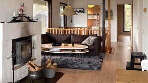 Ein gemütliches Wohnzimmer mit Kamin, einem runden Couchtisch, einer Couch und einem Essbereich.