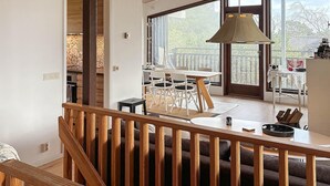 A modern kitchen with a dining area, large windows, and a wooden staircase. - 3 bedroom cozy home in Yngsjö (Yngsjö)