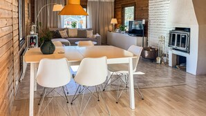 Een modern ingerichte blokhut met een eethoek, bank, televisie, open haard en houten vloeren.